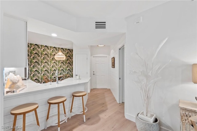 kitchen featuring hanging light fixtures, a kitchen bar, and light wood-type flooring