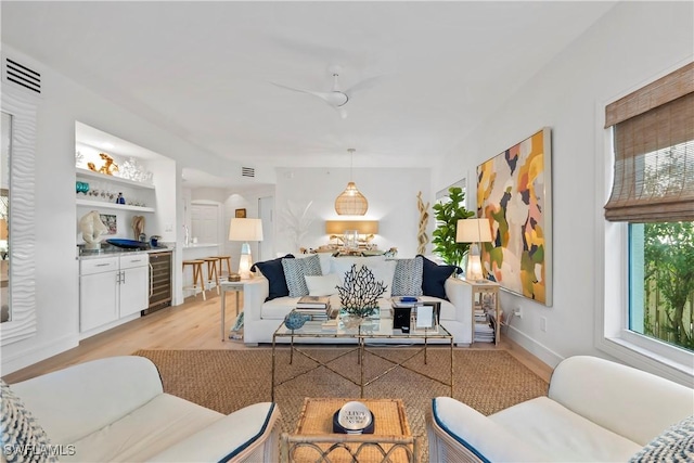 living room featuring wine cooler, built in features, and light wood-type flooring