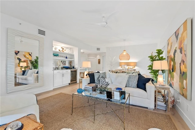 living room with wine cooler, indoor bar, and light hardwood / wood-style flooring