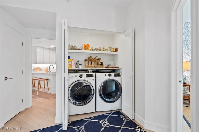 laundry area with sink, hardwood / wood-style floors, and independent washer and dryer