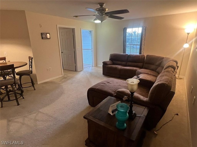 living room featuring light carpet, baseboards, and a ceiling fan