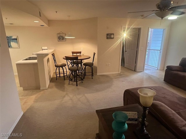 dining space featuring light carpet, ceiling fan, and baseboards