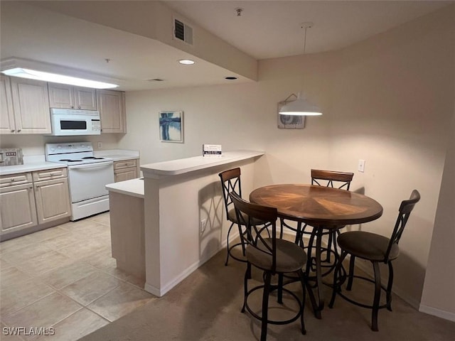 kitchen with a breakfast bar area, a peninsula, white appliances, visible vents, and light countertops