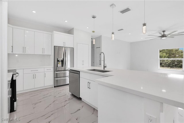 kitchen featuring sink, white cabinetry, hanging light fixtures, appliances with stainless steel finishes, and ceiling fan