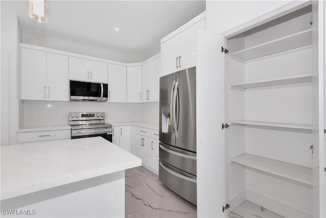 kitchen featuring hanging light fixtures, white cabinets, and appliances with stainless steel finishes