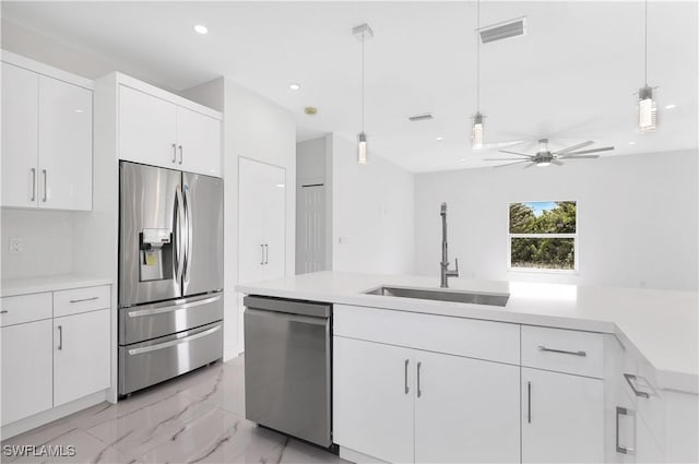 kitchen featuring appliances with stainless steel finishes, sink, pendant lighting, and white cabinets