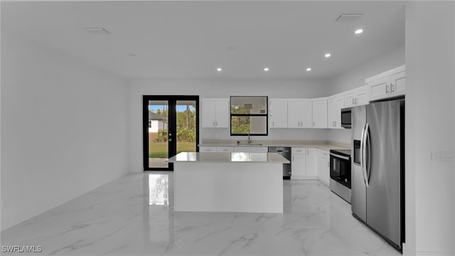 kitchen featuring a kitchen island, white cabinetry, sink, stainless steel appliances, and french doors