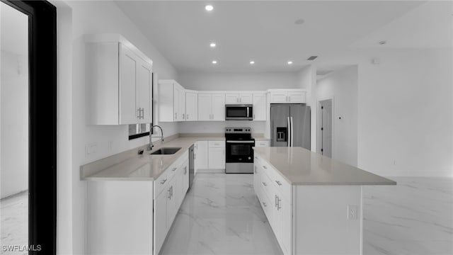 kitchen with stainless steel appliances, sink, a kitchen island, and white cabinets