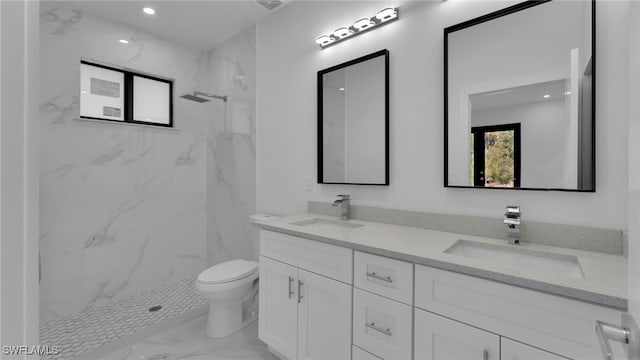 bathroom with vanity, toilet, and a tile shower