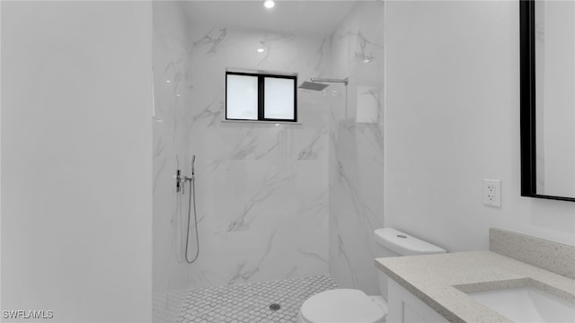 bathroom with tiled shower, vanity, and toilet