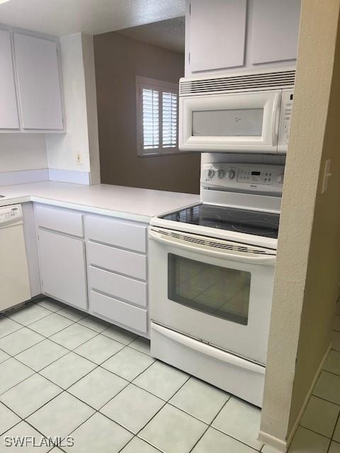 kitchen featuring white appliances, white cabinets, light tile patterned floors, and light countertops