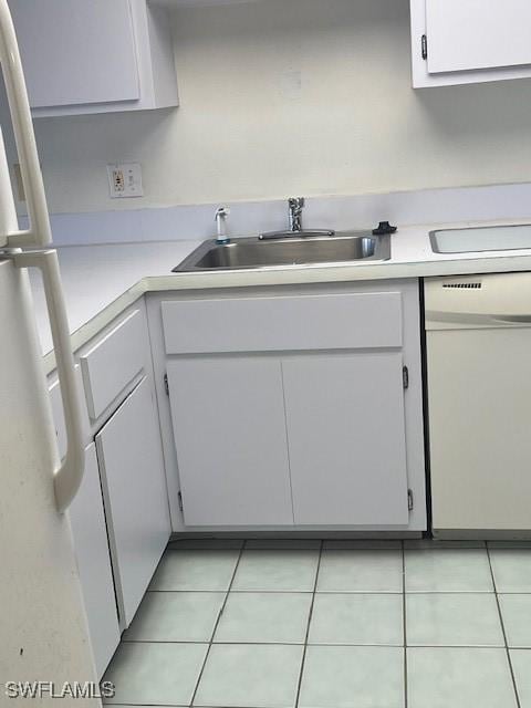 kitchen with a sink, white cabinetry, white appliances, light countertops, and light tile patterned floors