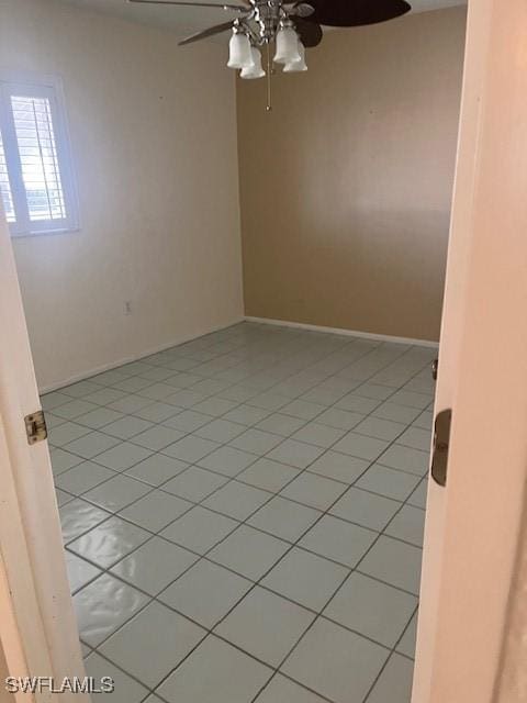 empty room with ceiling fan, baseboards, and light tile patterned flooring