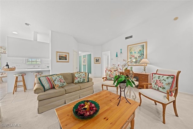 living area with vaulted ceiling, light tile patterned floors, visible vents, and light colored carpet