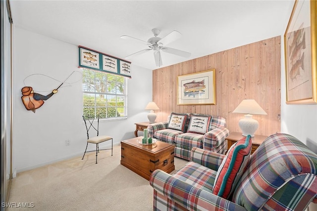 carpeted living room featuring wooden walls, baseboards, and a ceiling fan