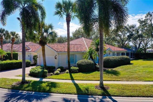 mediterranean / spanish-style home featuring a front lawn, decorative driveway, an attached garage, and stucco siding