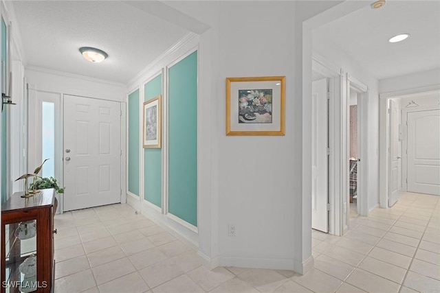 foyer with light tile patterned floors, ornamental molding, and baseboards