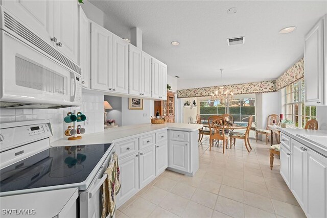 kitchen featuring white appliances, visible vents, white cabinetry, light countertops, and decorative backsplash