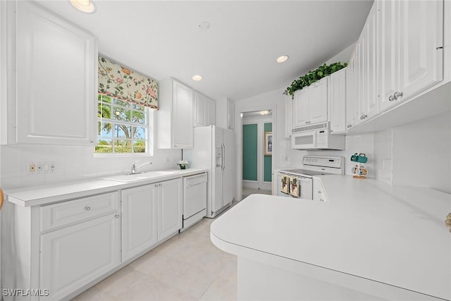 kitchen featuring white appliances, light countertops, a sink, and decorative backsplash