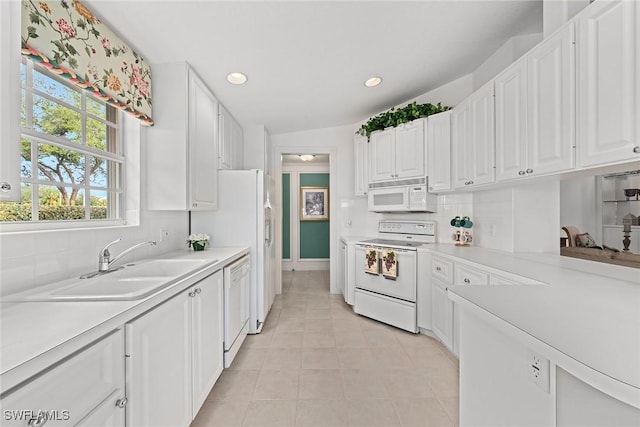 kitchen with white appliances, white cabinetry, light countertops, and a sink