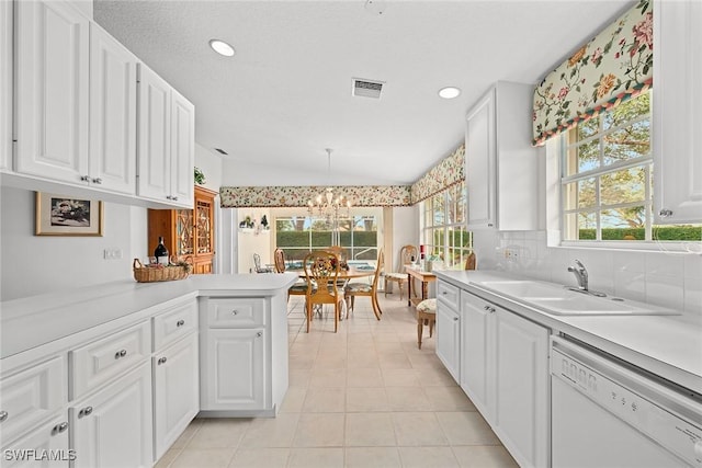 kitchen featuring light countertops, visible vents, white cabinets, white dishwasher, and a sink