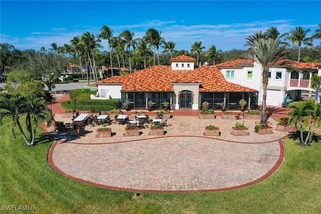 back of house with a tile roof, a yard, and stucco siding