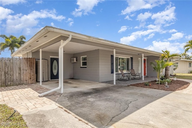 single story home featuring a carport, a wall mounted AC, and a porch