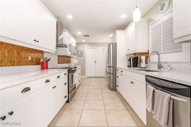 kitchen featuring sink, white cabinetry, stainless steel appliances, decorative light fixtures, and wall chimney exhaust hood