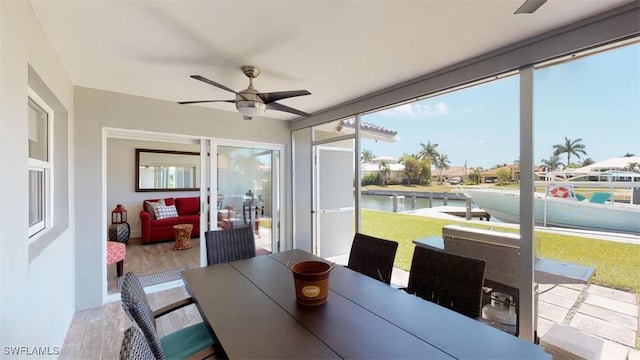 sunroom / solarium with a water view and ceiling fan