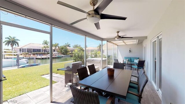 sunroom / solarium with a water view and ceiling fan