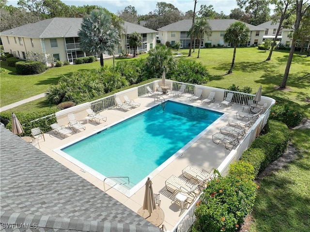 view of pool with a patio and a lawn