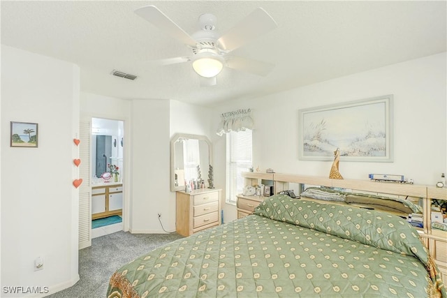 carpeted bedroom with ensuite bath and ceiling fan