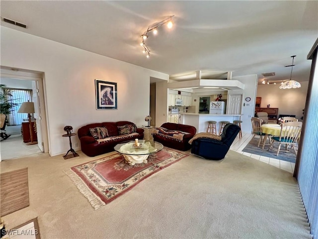 carpeted living area with rail lighting and visible vents