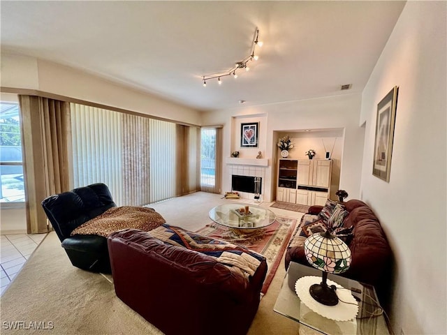 living area with light tile patterned floors, visible vents, and a tiled fireplace