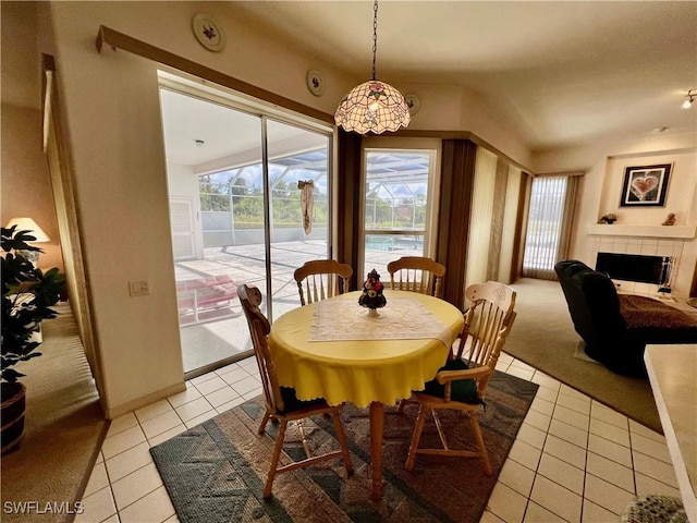 dining area featuring light tile patterned flooring, a tile fireplace, and light colored carpet