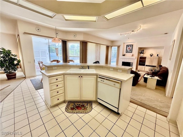 kitchen with light tile patterned floors, light countertops, open floor plan, white dishwasher, and a sink