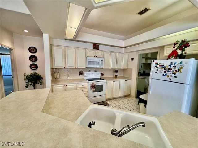 kitchen featuring light tile patterned flooring, white appliances, visible vents, light countertops, and decorative backsplash