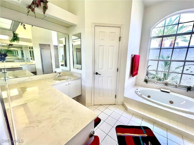 bathroom with tile patterned flooring, vanity, and a tub with jets