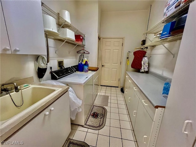 laundry room featuring cabinet space, light tile patterned floors, washer and clothes dryer, and a sink