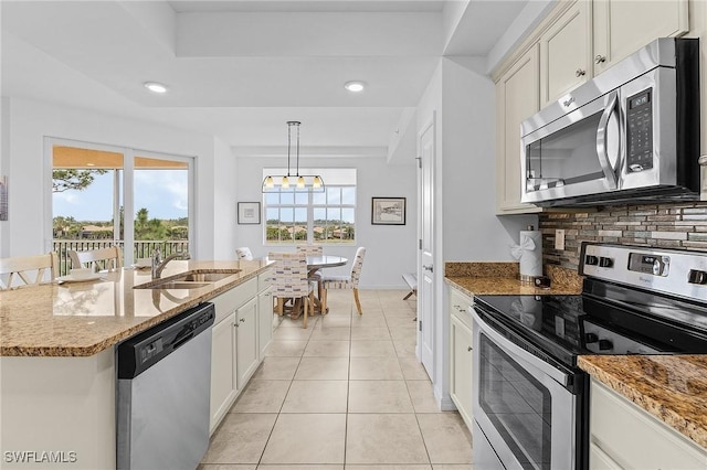 kitchen with light tile patterned flooring, sink, decorative light fixtures, appliances with stainless steel finishes, and backsplash