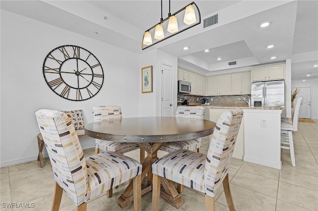 tiled dining space with a tray ceiling