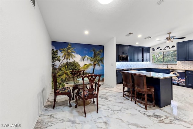 kitchen with blue cabinets, sink, backsplash, a kitchen bar, and stainless steel appliances