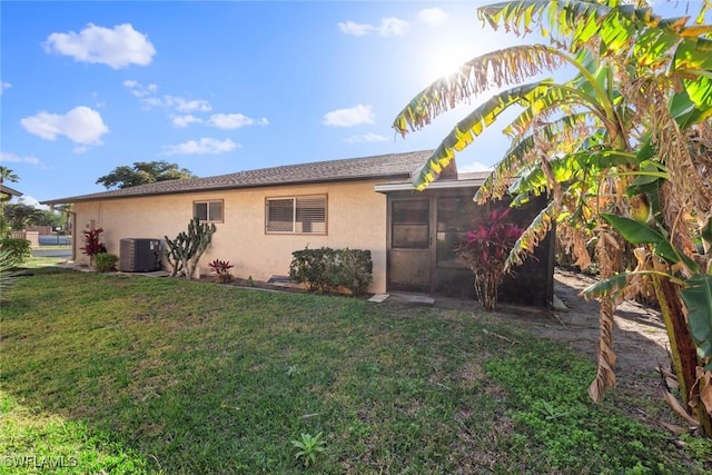 exterior space with central AC unit and a lawn