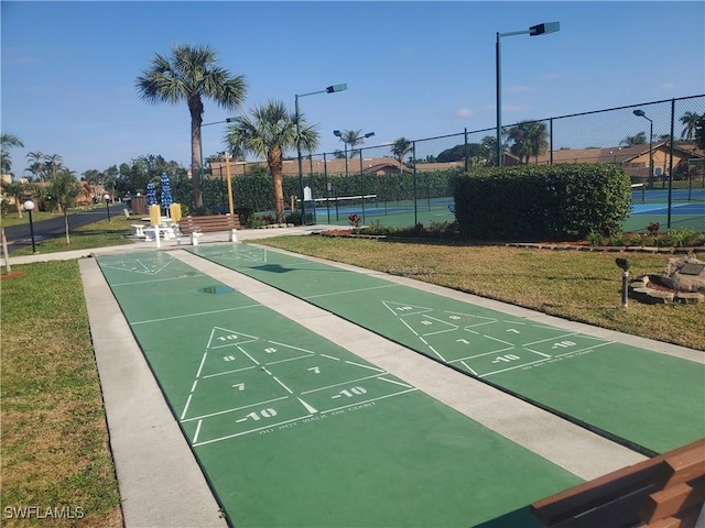 view of property's community with tennis court and a lawn