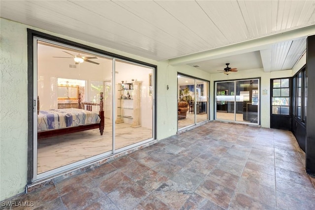 unfurnished sunroom featuring wood ceiling and ceiling fan