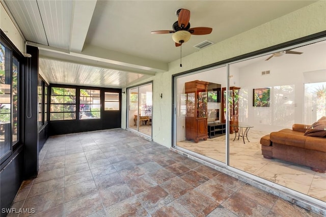 sunroom with ceiling fan and beam ceiling