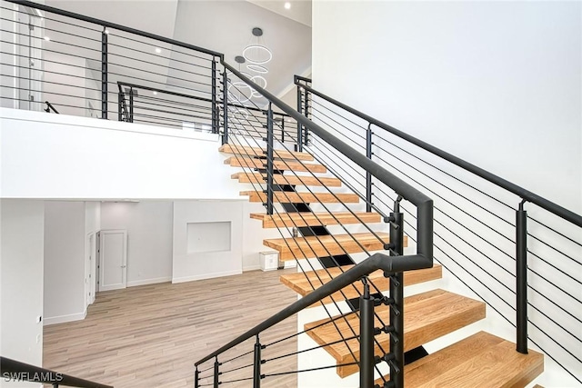 stairway with hardwood / wood-style flooring and a towering ceiling