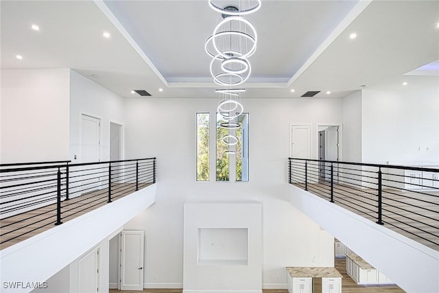 stairs with an inviting chandelier, a tray ceiling, and a high ceiling