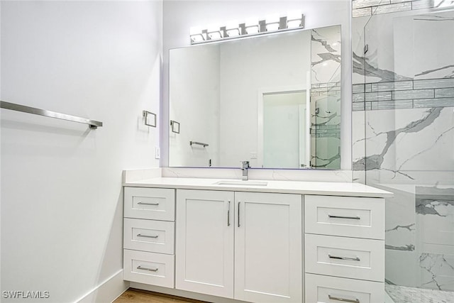 bathroom featuring a marble finish shower and vanity