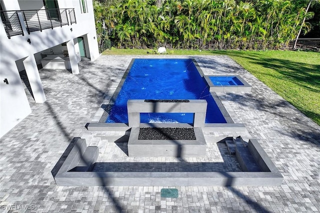 view of pool featuring pool water feature, a patio area, and a lawn